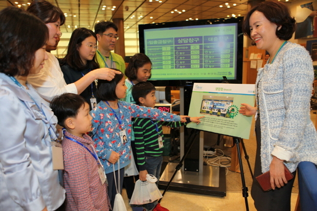 8일 종로구 공평동 소재 SC은행 본점에서 열린 ‘수퍼히어로의 하루’ 행사에 참여한 SC은행 임직원과 자녀들이 SC은행 박현주 전무(우측)로부터 영업점의 객장 업무에 대해 설명을 듣고 있다.