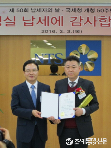 류득현 서초세무서장이 모범납세자로 선정된 (주)세명차양시스템 박영남 대표이사에게 꽃다발을 전달한 후 기념촬영을 하고 있다.