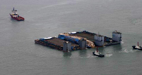 24일 오후 전남 진도군 세월호 사고 해역에서 수면 위 13m까지 올라온 세월호가 2척의 잭킹바지선에 와이어로 묶여 반잠수식 선박으로 이동을 기다리고 있다 / 연합뉴스